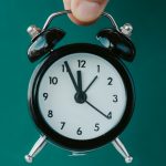 Tiny Alarm Clock Held By Fingers